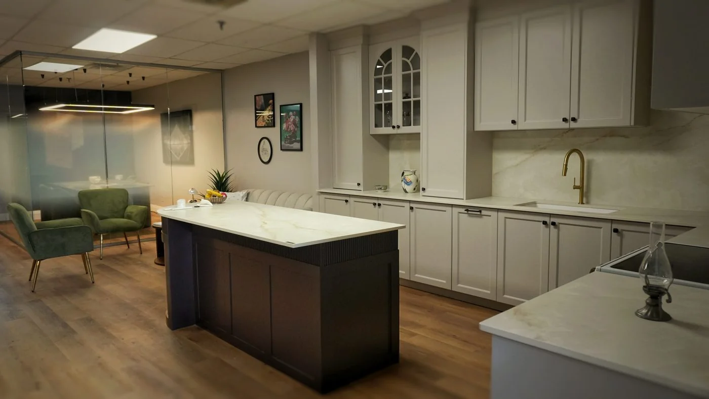 Office kitchenette with cream cabinets, arched glass upper doors and a dark island with a quartz top, next to a seating area