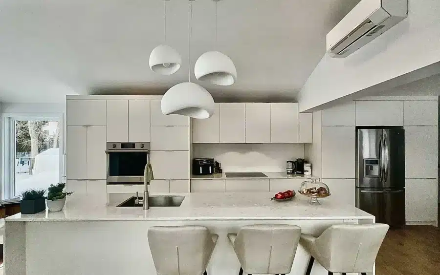 Façades d’armoires blanches en MDF et îlot cascade en quartz dans la cuisine Limakdéco de Laval