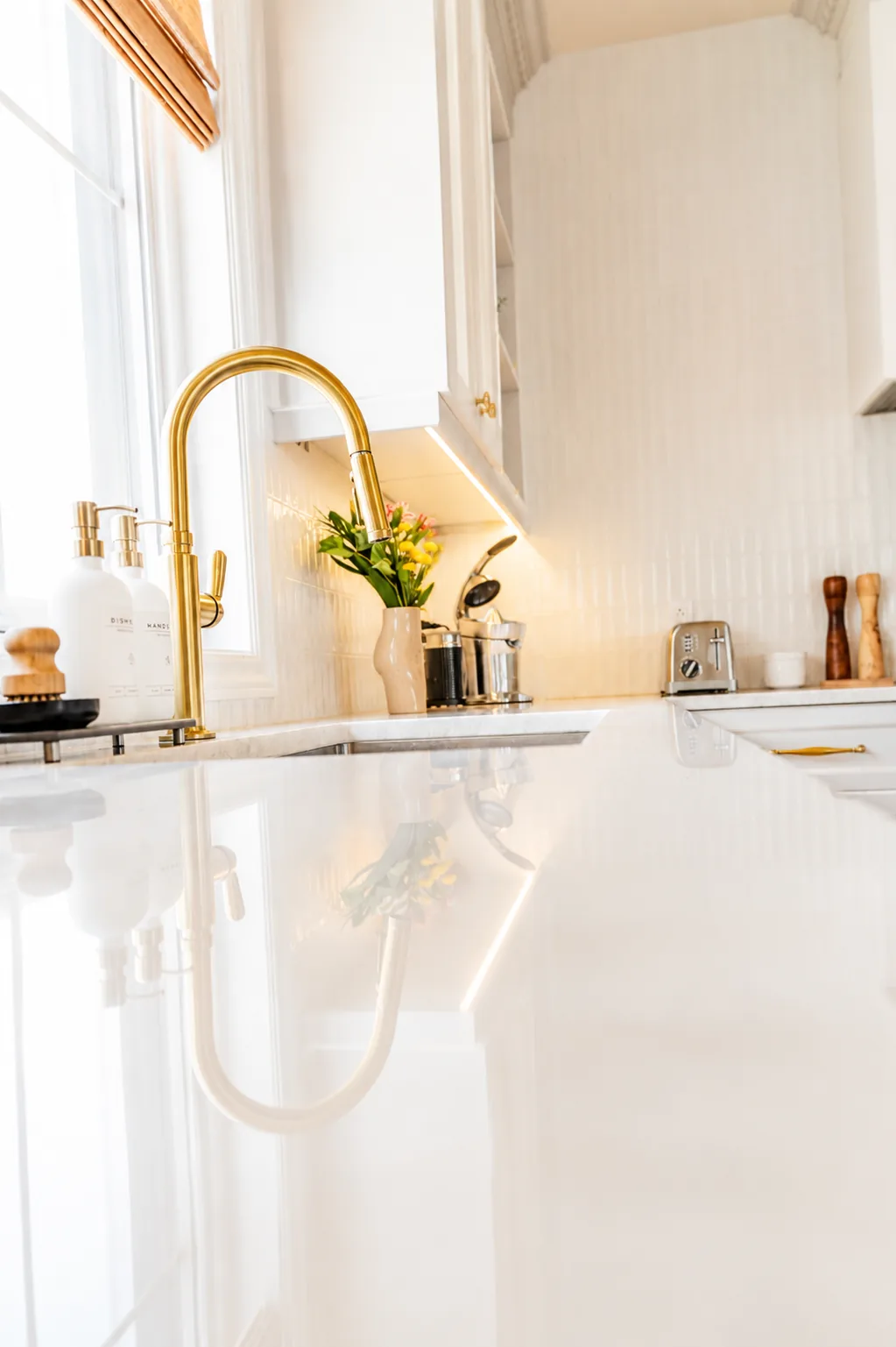 Brushed brass pull down faucet over an undermount sink with Taj Mahal quartzite counter in Terrebonne
