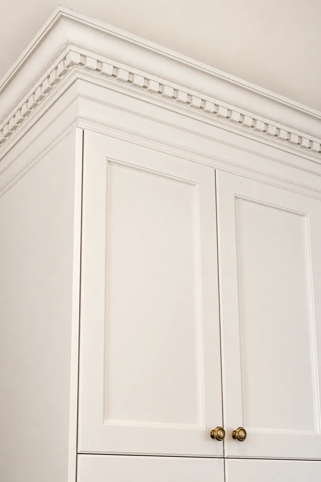 Dentil crown moulding detail on cream shaker cabinets with brass knobs in a custom Terrebonne kitchen