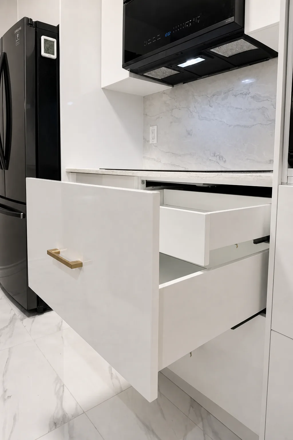 Hidden inner drawer inside a glossy white kitchen drawer with brass pull, Pointe-Claire