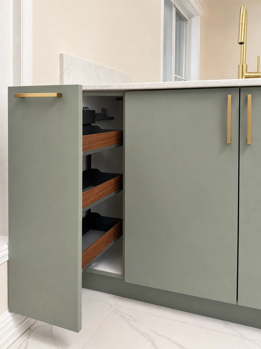 Pull out spice and oil organizer with walnut trays in the sage green island cabinets, Pointe-Claire