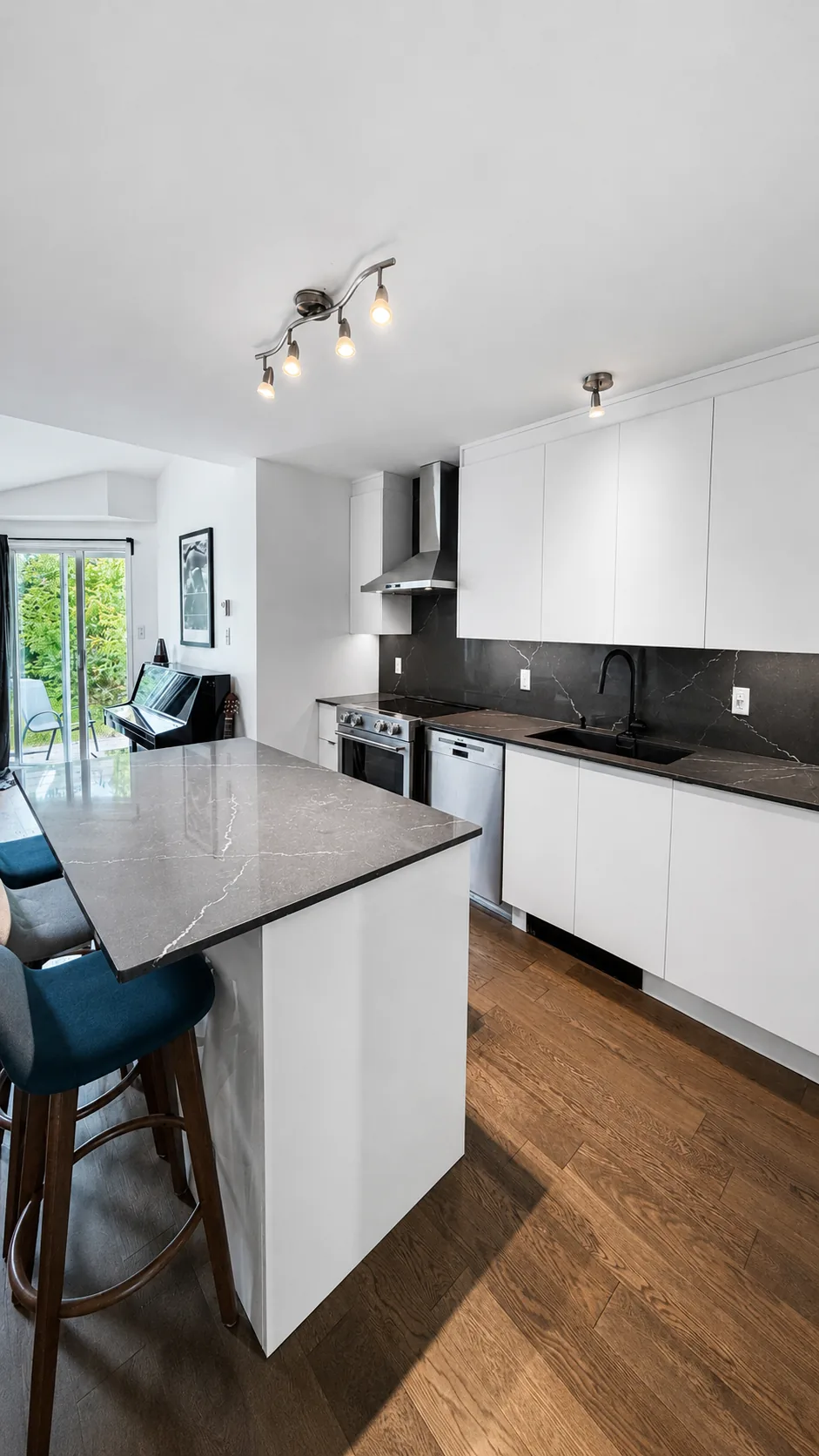 Cuisine rénovée avec îlot en quartz noir ouverte sur le salon, plancher neuf en bois franc d'ingénierie, Pierrefonds