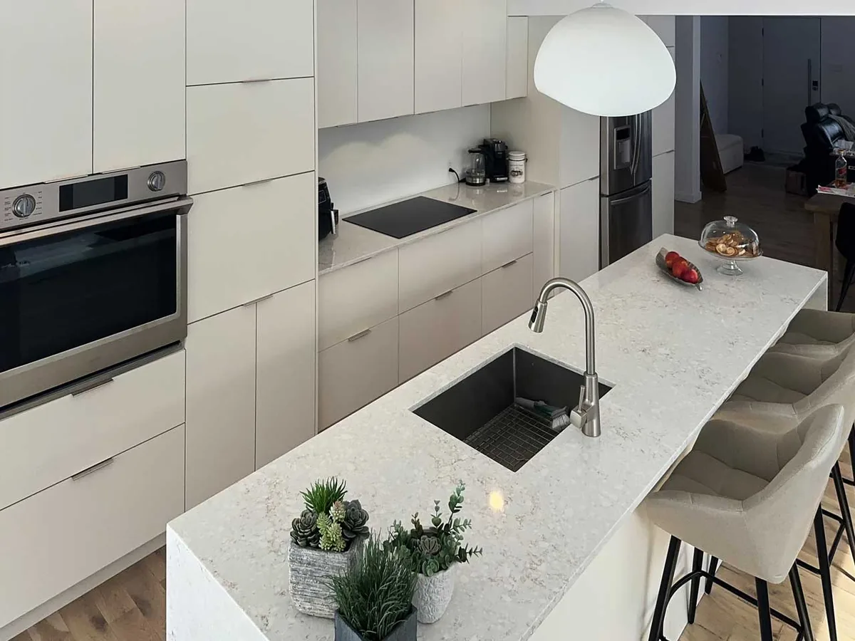 Dessus d'îlot en quartz avec l'évier placé à une extrémité pour garder la surface continue, cuisine de Laval