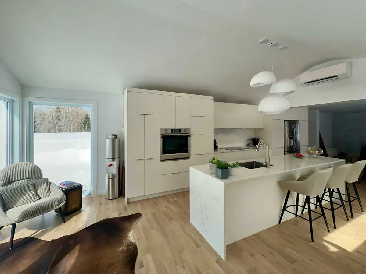 Seconde extrémité en cascade à onglet de l'îlot en quartz, ouverte sur le salon d'une maison neuve à Laval