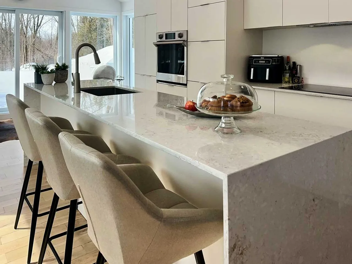 Extrémité en cascade à onglet d'un grand îlot en quartz Radianz Alluring, cuisine blanc mat à Laval