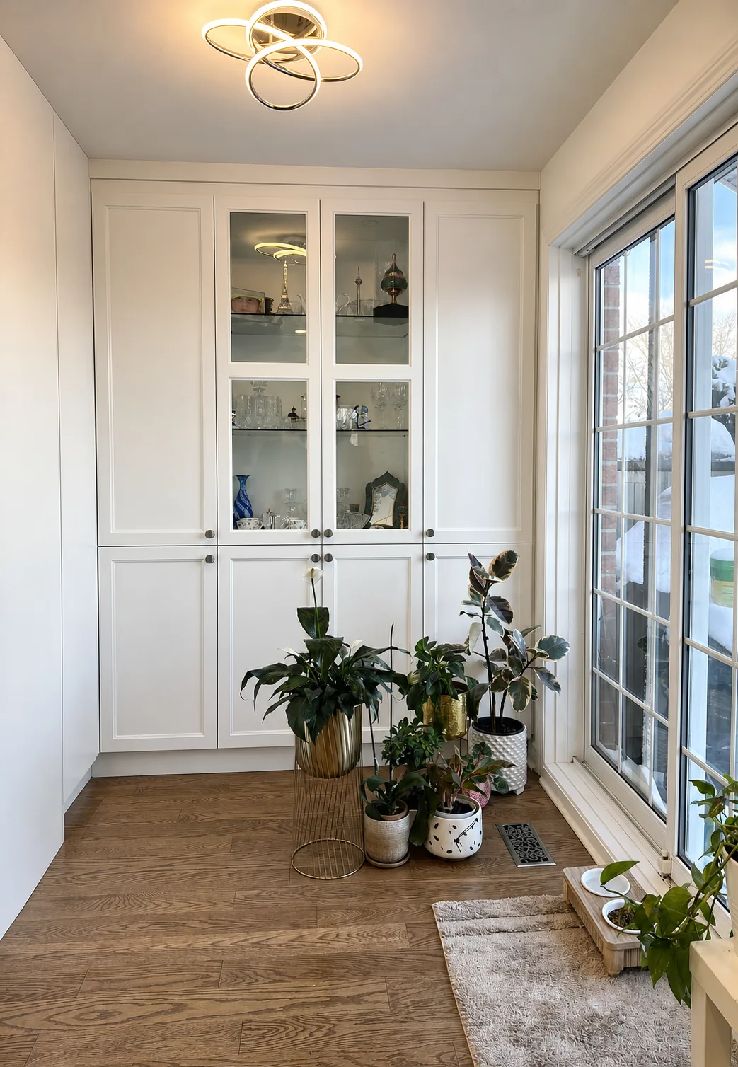 Floor to ceiling white display cabinet with glass doors on the extended side wall of a Bois-Franc kitchen
