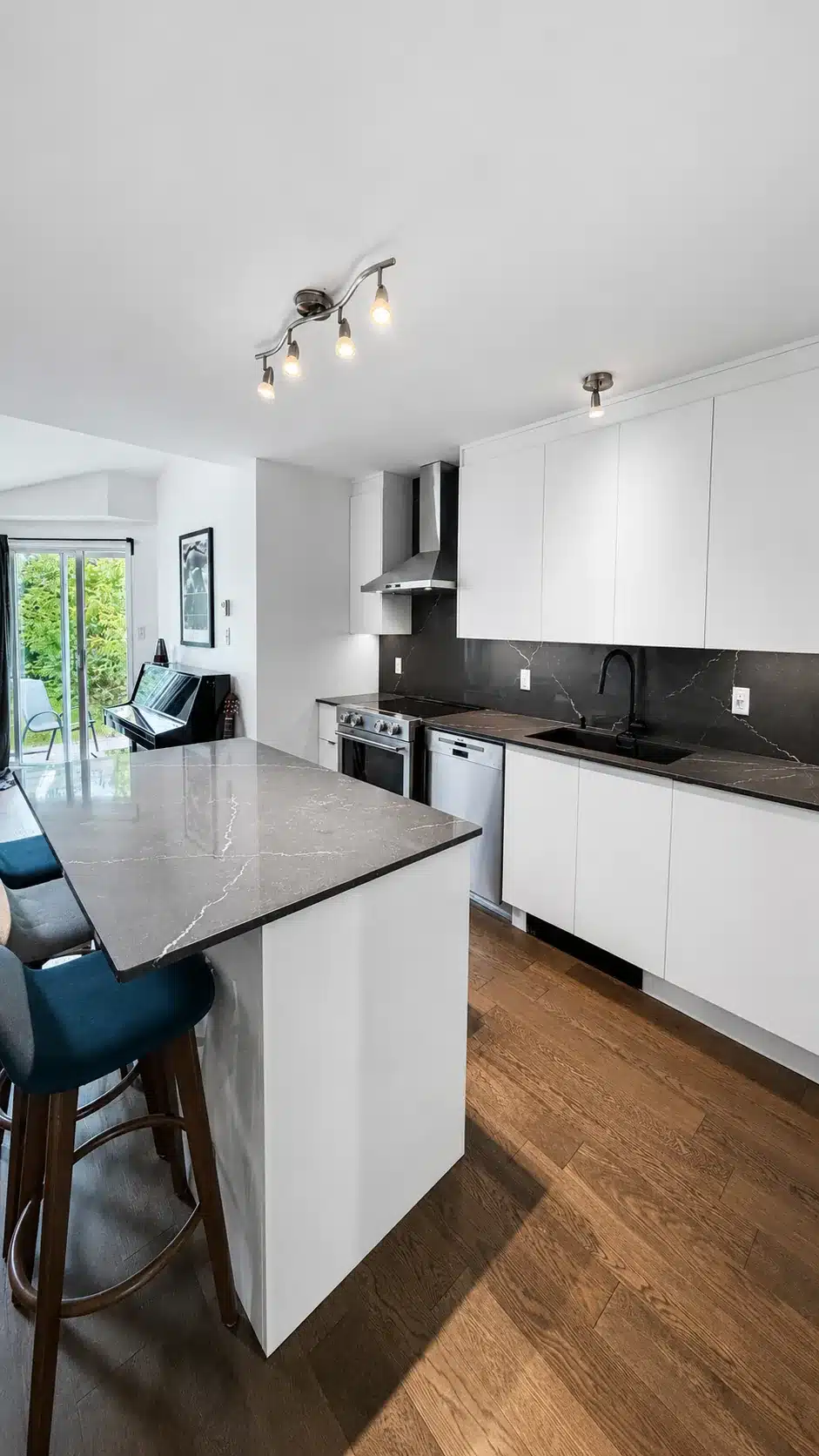 Engineered hardwood floor beside the white cabinets and the black quartz-topped island in the Pierrefonds kitchen