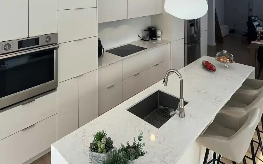 Tall cabinet wall with built-in ovens beside the island in Limakdéco’s Laval kitchen