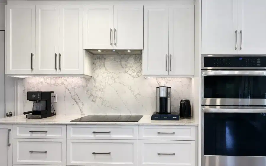 Renoir quartz countertop and full-height backsplash in the white shaker kitchen in Bois-Franc