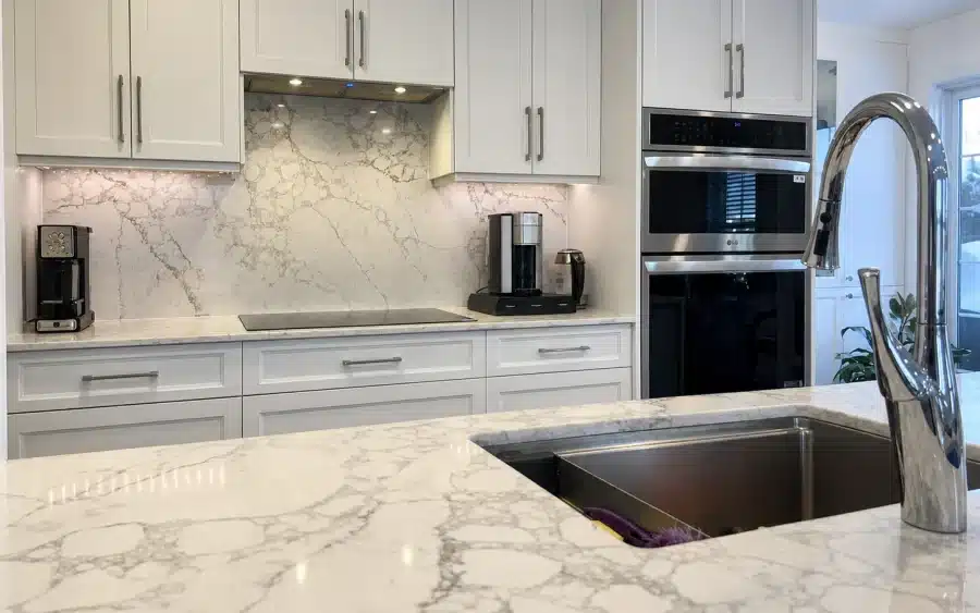 Shaker cabinets and a full-height quartz backsplash seen from the island in Limakdéco’s Bois-Franc kitchen